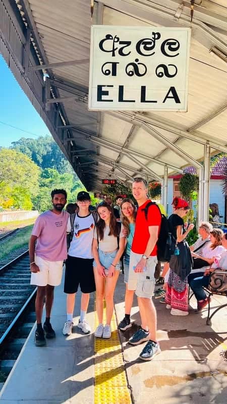 Family posing with their local expert tour guide at Ella Railway Station in Sri Lanka, surrounded by the scenic charm of the hill country railway.